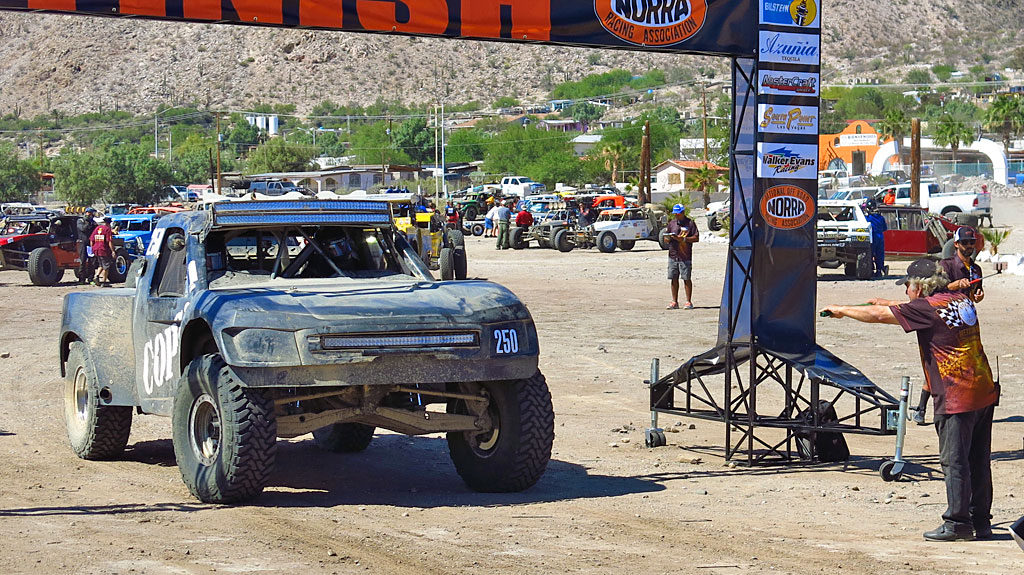 John leaves the starting line at the direction of NORRA Director Mike Pearlman. It was Pearlman’s late father Ed, along with others, who established the first running of the NORRA Mexican 1000 off-road rally in November 1967.